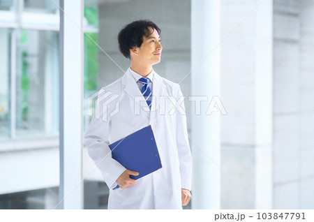 病院の廊下に立つ白衣の若い男性医師 103847791