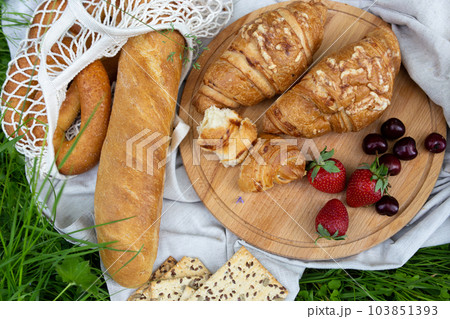 Picnic in the field with berries, juice, cheese, sausage and sweet croissants Picnic in the field with berries, juice, cheese, sausage and sweet croissants 103851393