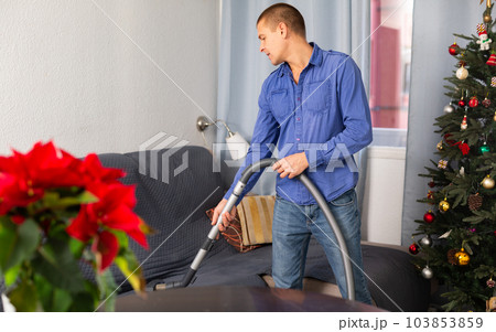 Man vacuuming room in his house before christmas 103853859