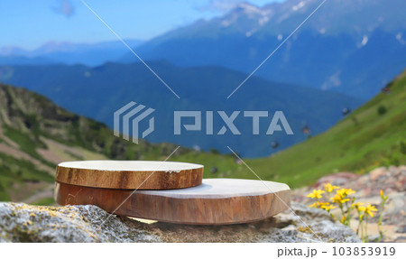 The podium is made of wood sawn with a natural background. Front showcase with a stand for the presentation of goods. With beautiful mountain views and blue sky. 103853919