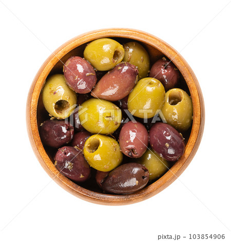 Pitted Kalamata and green olives, in a wooden bowl. Mix of organic Greek olives, green and black, with herbs, preserved in native olive oil. Popular table olives, used as snack, appetizer or garnish. 103854906