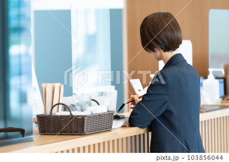 ホテルのフロントで手続きするビジネスマン（出張・予約） 103856044