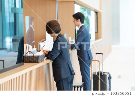 ホテルのフロントで手続きするビジネスマン（出張・予約） 103856051