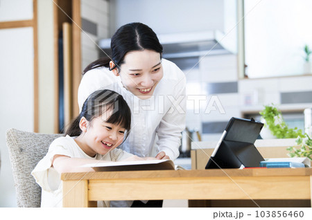 自宅で娘に勉強を教える母親 自宅で娘に勉強を教える母親 103856460