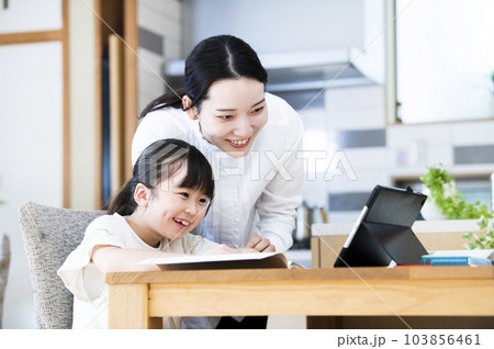 自宅で娘に勉強を教える母親 自宅で娘に勉強を教える母親 103856461