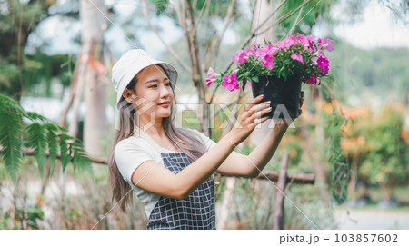 Young women doing hobbies taking care of plants, watering, shoveling flowers. In the garden during the break from work Young women doing hobbies taking care of plants, watering, shoveling flowers. In the garden during the break from work 103857602