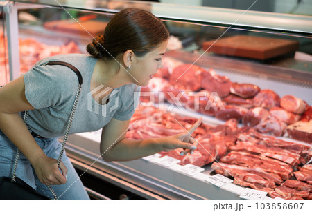 Female customer points with finger and orders beef brisket and sirloin Female customer points with finger and orders beef brisket and sirloin 103858607