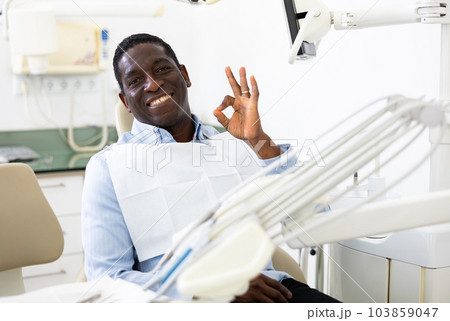 Portrait of positive man making ok gesture, sitting on dental chair 103859047