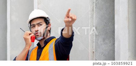Young man engineer using radio command with worker in construction site. 103859921