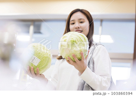 スーパーでキャベツを持ってどっちを買うか選ぶ若い女性 スーパーでキャベツを持ってどっちを買うか選ぶ若い女性 103860394