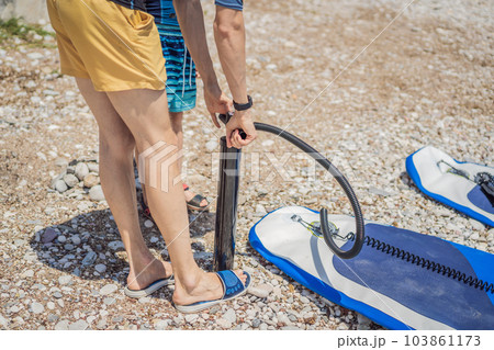 Father and son inflates pump paddle Board, fashionable modern entertainment Father and son inflates pump paddle Board, fashionable modern entertainment 103861173