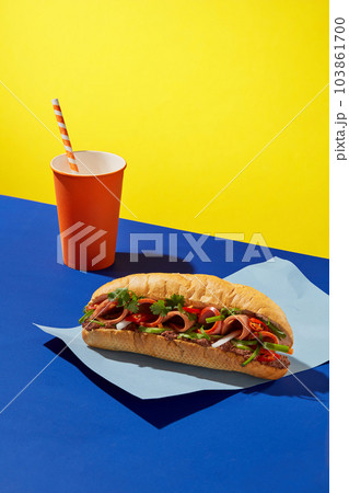 Front view of delicious bread with a orange disposable paper cup decorated on color paper background. Creative scene for advertising bread of Vietnamese with drinking. Copy space 103861700