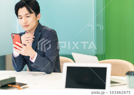 仕事中スマホで投資をするビジネスマン 103862675