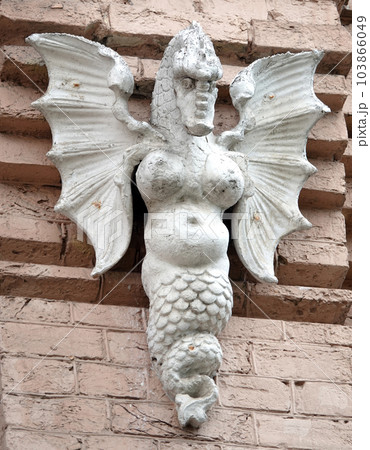 Kiev, Ukraine June 10, 2021: Sculpture of the Griffin - Dragon with a woman's breast, wings and a man's face on the facade of a building in the center of Kiev 103866049