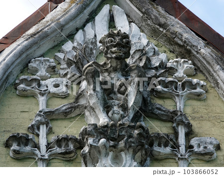 Kiev, Ukraine June 10, 2021: Sculpture of a Griffin in a human figure with bat wings on the facade of a building in the center of Kiev Kiev, Ukraine June 10, 2021: Sculpture of a Griffin in a human figure with bat wings on the facade of a building in the center of Kiev 103866052