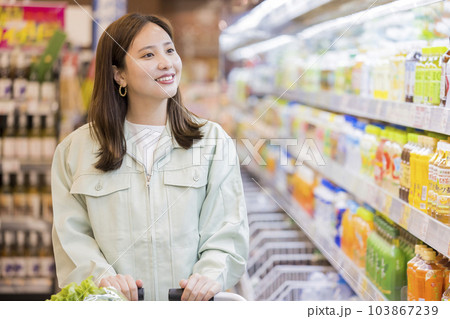 スーパーで作業着を着たまま買い物をする若い女性 103867239