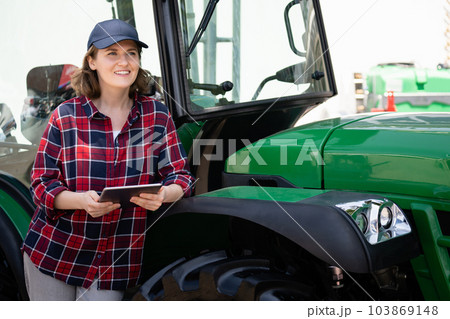 Woman farmer and green agricultural tractor 103869148