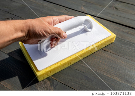 Construction planer with a sponge in a man's hand. Wood texture background 103871138