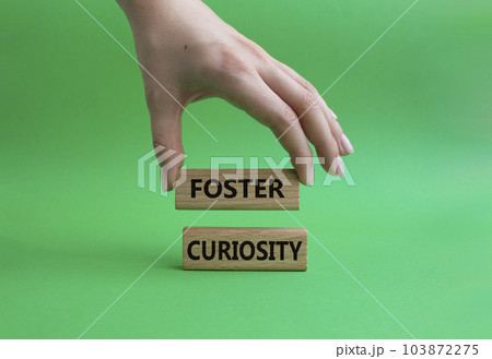 Foster curiosity symbol. Concept word Foster curiosity on wooden blocks. Beautiful green background. Businessman hand. Business and Foster curiosity concept. Copy space Foster curiosity symbol. Concept word Foster curiosity on wooden blocks. Beautiful green background. Businessman hand. Business and Foster curiosity concept. Copy space 103872275