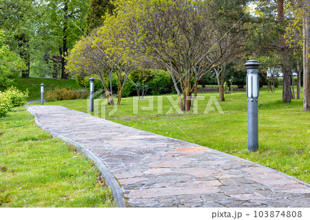 A stone-paved garden path runs diagonally across the spring garden. A stone-paved garden path runs diagonally across the spring garden. 103874808