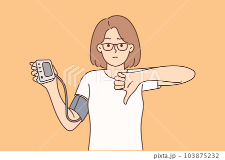 Woman holding tonometer to check cardio health and heart disease shows thumb down 103875232