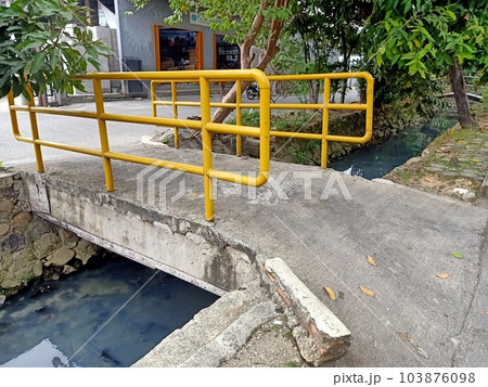Yellow little bridge over sewerage  103876098