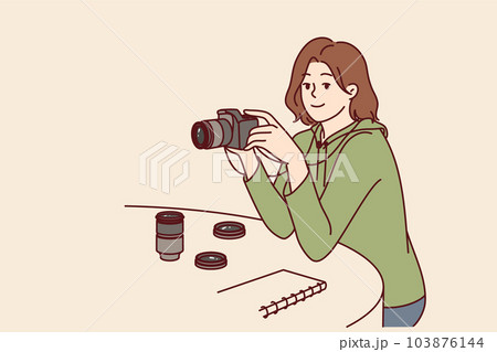 Woman photographer with camera sits at table choosing lens for photo essay or creating portrait 103876144