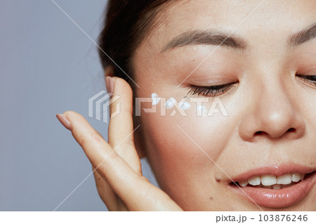 Closeup on modern asian female with facial cream on face Closeup on modern asian female with facial cream on face 103876246