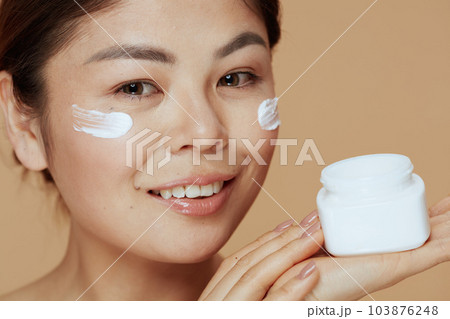 Portrait of modern asian female with facial cream jar 103876248