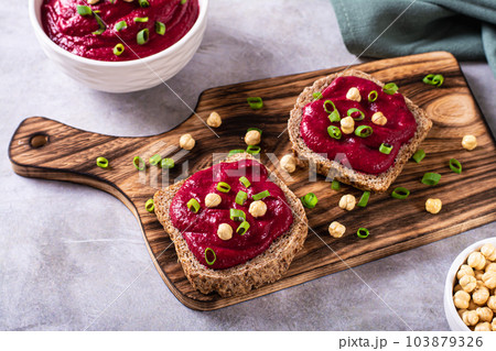 Appetizing rye bread bruschettas with beetroot hummus and chives on a cutting board 103879326