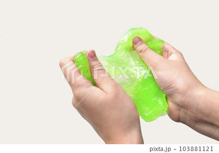 Hand Playing with textured slime on white background. Teen hand holding green shining slime with bubbles, stretching gooey substance. Teenage Girl squeezing slime toy to the sides. Liquid toy. Handgum Hand Playing with textured slime on white background. Teen hand holding green shining slime with bubbles, stretching gooey substance. Teenage Girl squeezing slime toy to the sides. Liquid toy. Handgum 103881121