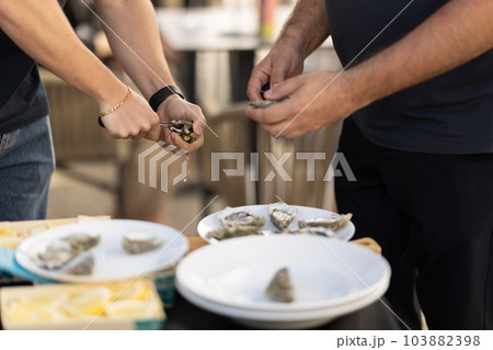 Two men open oysters with a knife Two men open oysters with a knife 103882398