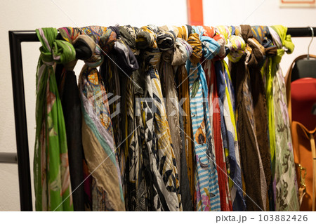 Multi-colored light women's scarves tied on a rod in the store Multi-colored light women's scarves tied on a rod in the store 103882426