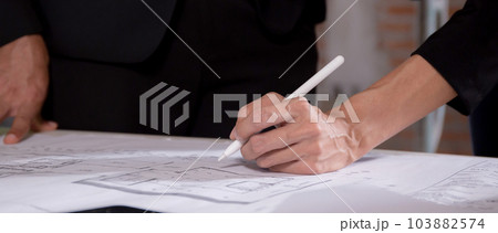 Closeup hands young caucasian architect woman looking laptop and working drawing blueprint. 103882574