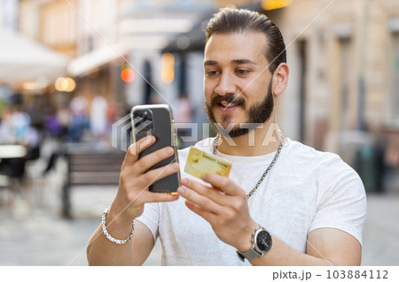 Young man using credit bank card smartphone while transferring money, purchases online shopping Young man using credit bank card smartphone while transferring money, purchases online shopping 103884112