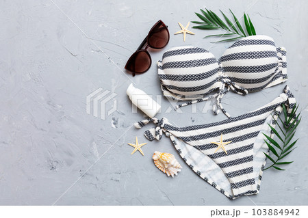 Woman swimwear and beach accessories flat lay top view on colored background Summer travel concept. bikini swimsuit, straw hat and seasheels. Copy space Top view 103884942