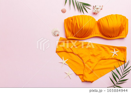 Woman swimwear and beach accessories flat lay top view on colored background Summer travel concept. bikini swimsuit, straw hat and seasheels. Copy space Top view 103884944