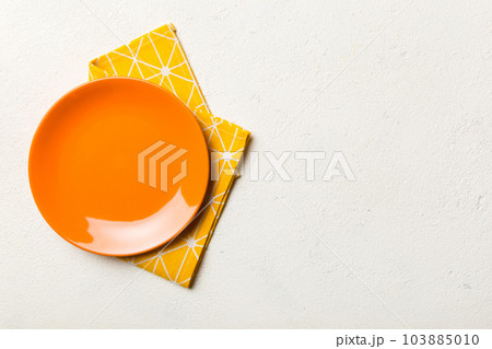Top view on colored background empty round red plate on tablecloth for food. Empty dish on napkin with space for your design 103885010