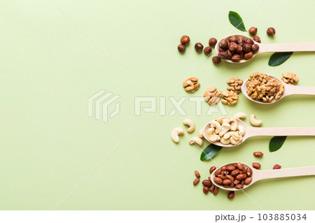 mixed nuts in white wooden spoon. Mix of various nuts on colored background. pistachios, cashews, walnuts, hazelnuts, peanuts and brazil nuts 103885034