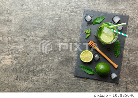 Caipirinha, Mojito cocktail, vodka or soda drink with lime, mint and straw on table background. Refreshing beverage with mint and lime in glass top view flat lay Caipirinha, Mojito cocktail, vodka or soda drink with lime, mint and straw on table background. Refreshing beverage with mint and lime in glass top view flat lay 103885046