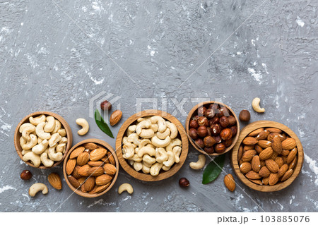 Assortment of nuts in wooden bowl on colored table. Cashew, hazelnuts, walnuts, almonds. Mix of nuts Top view with copy space 103885076