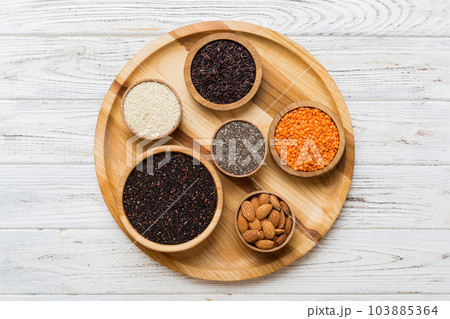Various superfoods in smal bowl on colored background. Superfood as rice, chia, quinoa, lentils, nuts, sesame seeds, almonds. top view 103885364