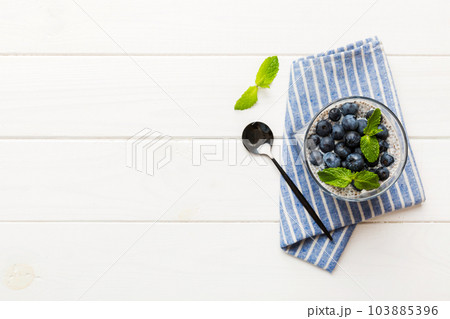 Healthy breakfast or morning with chia seeds vanilla pudding and blueberry berries on table background, vegetarian food, diet and health concept. Chia pudding with coconut milk and blueberry 103885396