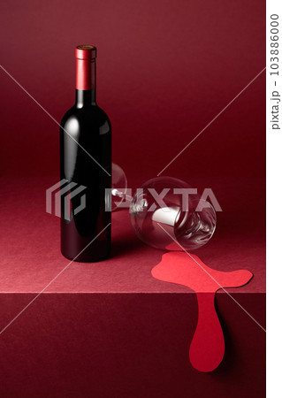 Bottle and glass of red wine on a red background. 103886000