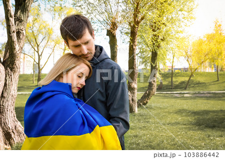 Young couple together with the flag of Ukraine in the park on a sunny day 103886442