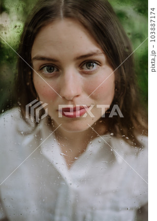 Portrait of young woman in botanical garden through foggy glass. Portrait of young woman in botanical garden through foggy glass. 103887174