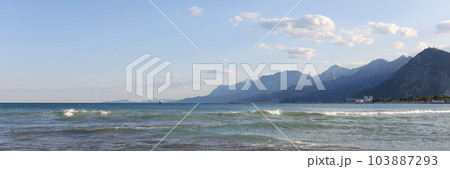 Pebble beach with cloudy blue sky on foggy mountains background 103887293