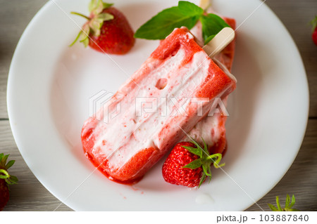 homemade strawberry ice cream on a stick in a plate with strawberries homemade strawberry ice cream on a stick in a plate with strawberries 103887840