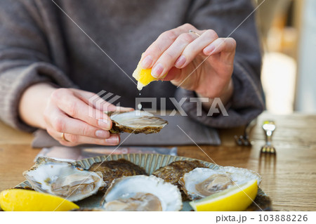 Beautiful Woman eating fresh oysters and drinking in restaurant. Seafood delicacies. Beautiful Woman eating fresh oysters and drinking in restaurant. Seafood delicacies. 103888226