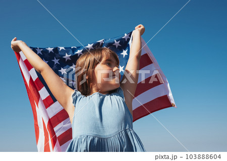 Portrait of a happy girl with the American flag in her hands against the background of the sky 103888604